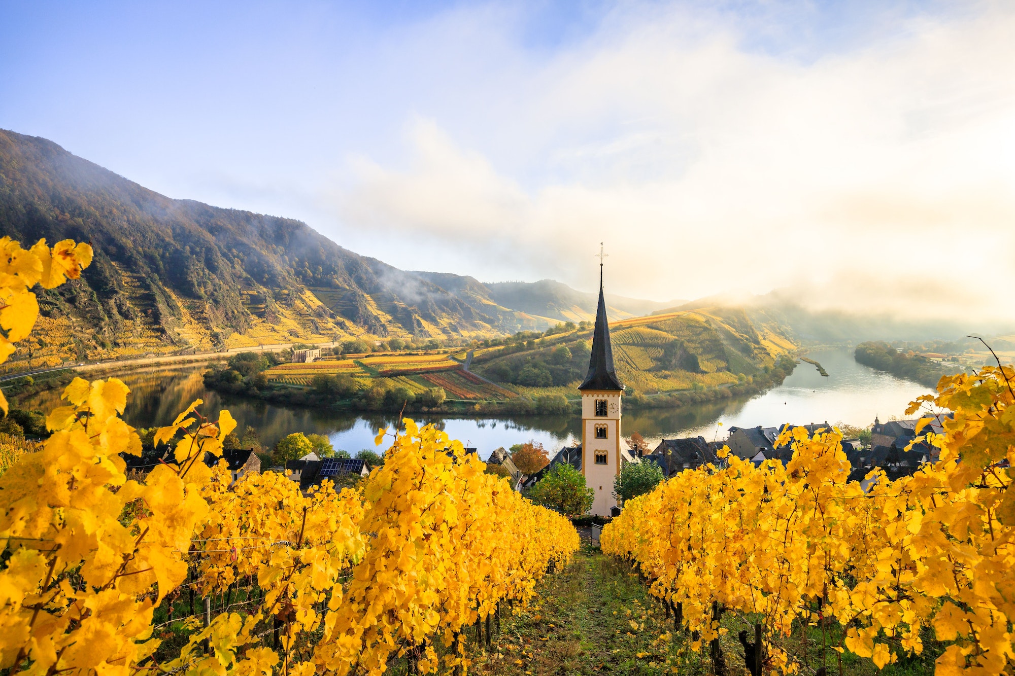 Picturesque white church on a hill in an idyllic mountain landscape: sunrise on the Moselle, Bremm