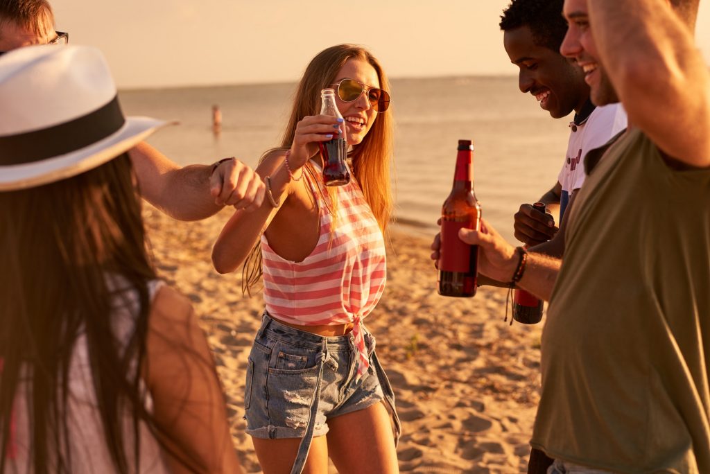 Carefree friends drinking beer at beach party