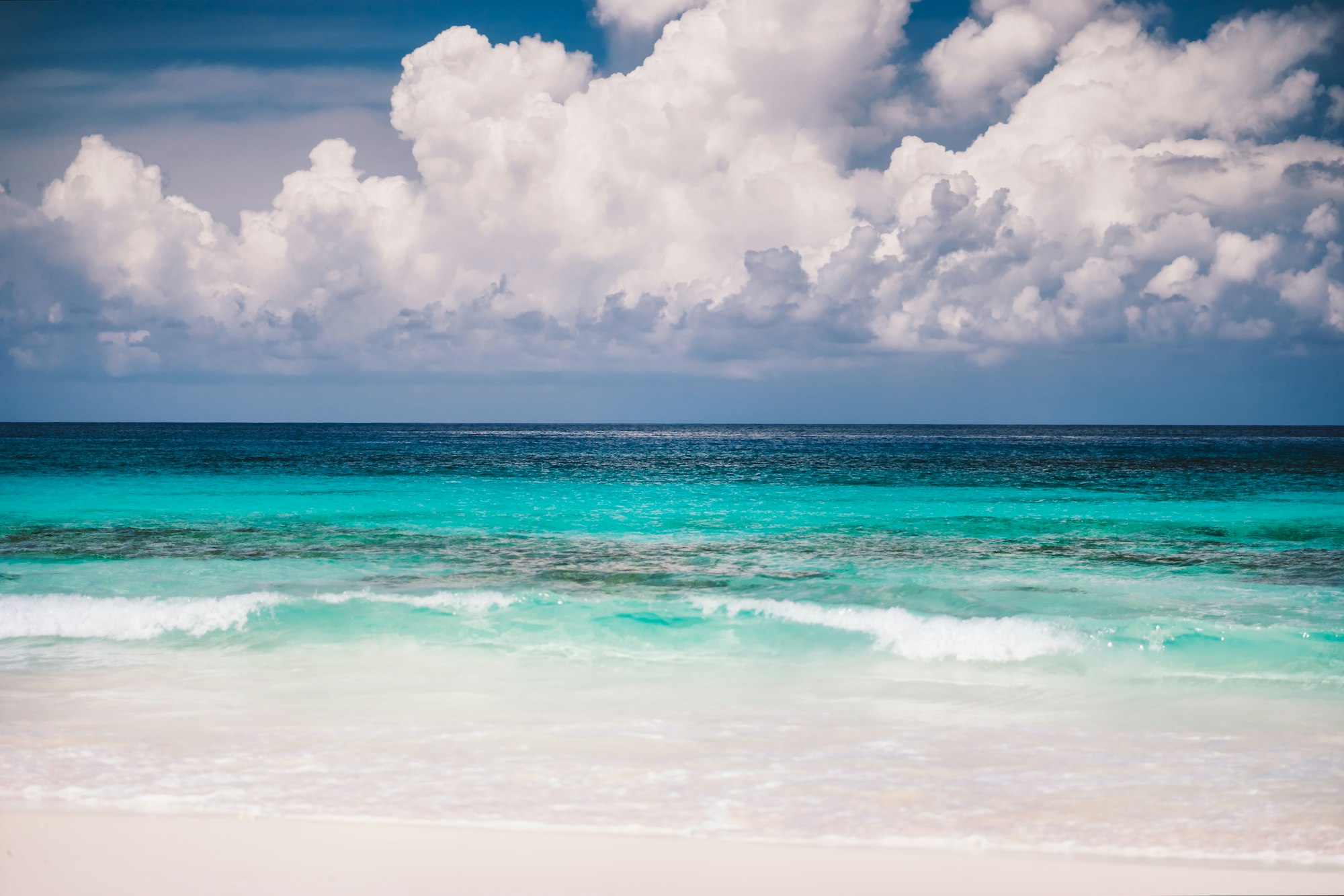 Sandy beach, blue ocean and white cloudscape at Mahe island, Seychelles